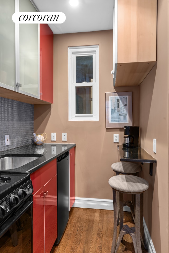 352 W 12th Street Maisonette, New York City, NY 10014 - kitchen featuring wood finished floors, baseboards, dark countertops, black gas range oven, and fridge
