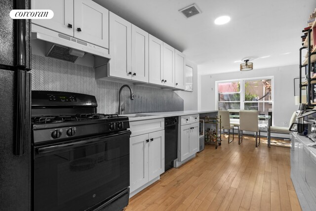 251 Powers St, New York City, NY 11211 - kitchen with black appliances, under cabinet range hood, white cabinetry, light countertops, and tasteful backsplash