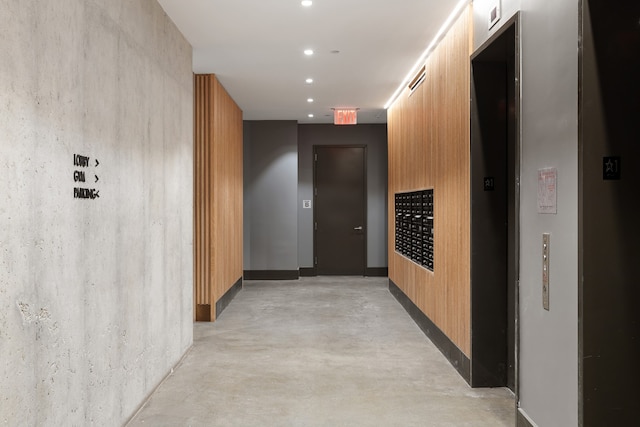 hallway featuring finished concrete flooring, recessed lighting, mail area, and elevator