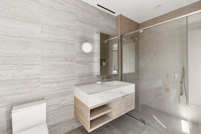 full bathroom featuring tile walls, a tile shower, vanity, and toilet