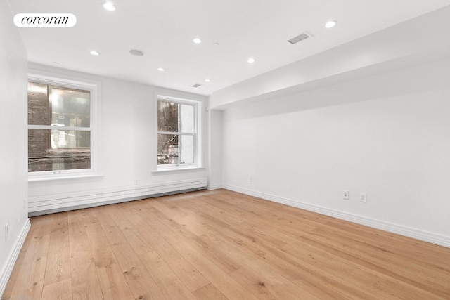 empty room featuring light wood-type flooring, baseboard heating, baseboards, and recessed lighting
