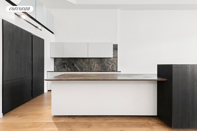 kitchen featuring backsplash, white cabinetry, butcher block countertops, a peninsula, and light wood-style flooring