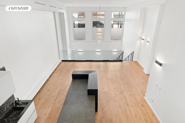 hall featuring an upstairs landing, wood finished floors, and baseboards