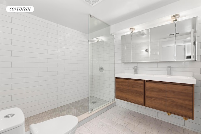 bathroom with toilet, a walk in shower, tile walls, and double vanity
