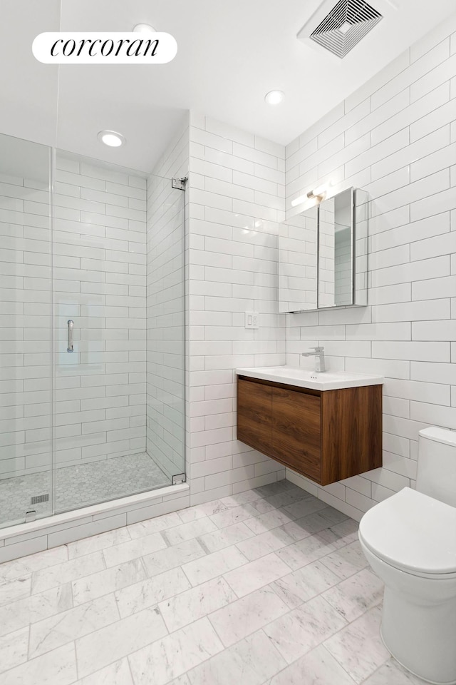 bathroom featuring tile walls, toilet, a shower stall, vanity, and recessed lighting