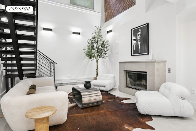 living area with a fireplace, a high ceiling, and stairs