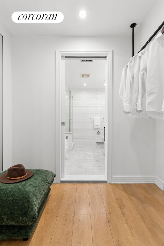 bathroom featuring tiled shower, wood finished floors, and recessed lighting