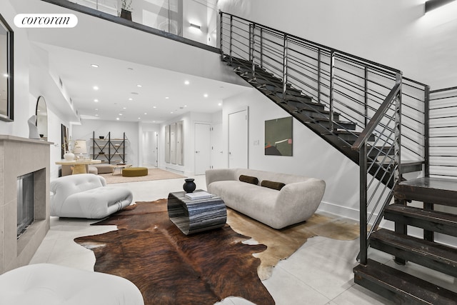 living room with stairs, recessed lighting, a tiled fireplace, tile patterned flooring, and baseboards
