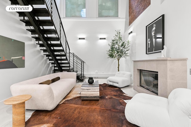 living room with stairway, a tiled fireplace, and a high ceiling