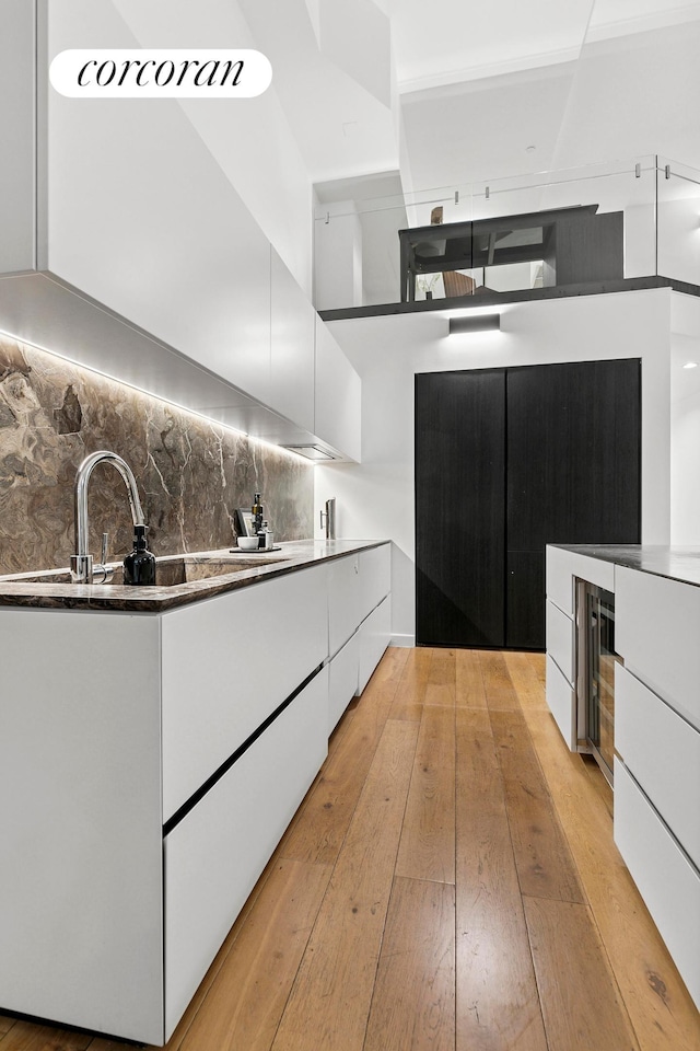 kitchen with modern cabinets, white cabinetry, and light wood-style floors
