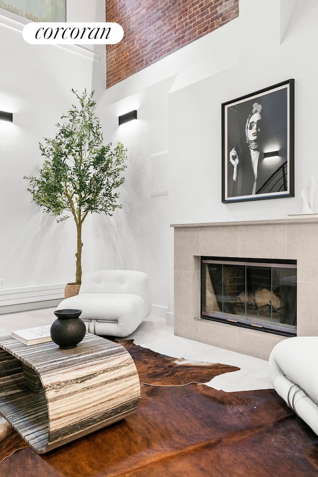 living area with a high ceiling, a tile fireplace, and baseboards