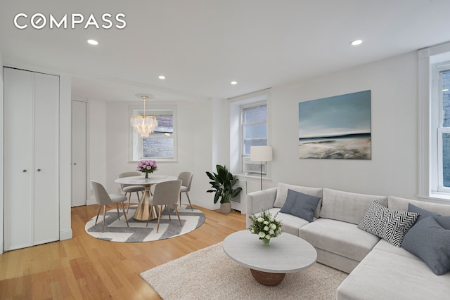 living area with wood finished floors, recessed lighting, a chandelier, and cooling unit