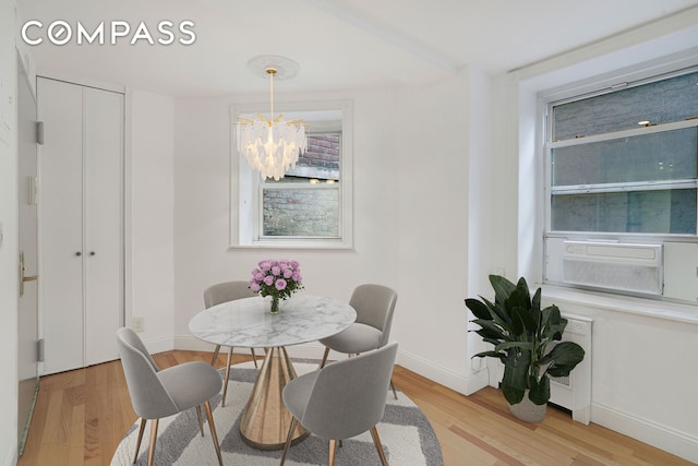 dining space with a chandelier, light wood-style floors, baseboards, and plenty of natural light