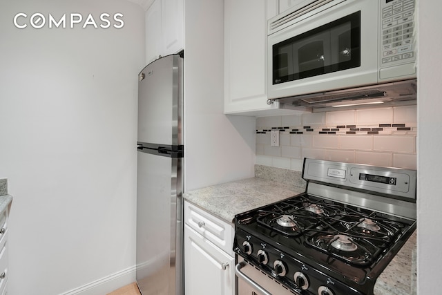 kitchen featuring appliances with stainless steel finishes, tasteful backsplash, white cabinetry, and baseboards