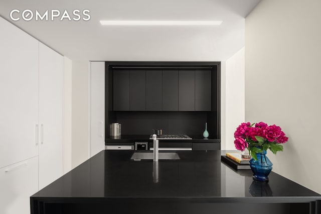 kitchen view of dark countertops, modern cabinets, and a sink