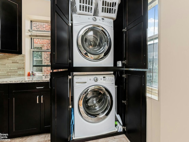 3750 Hudson Manor Ter Unit 5Cw, New York City, NY 10463 - laundry room with stacked washing machine and dryer, cabinet space, and light tile patterned flooring