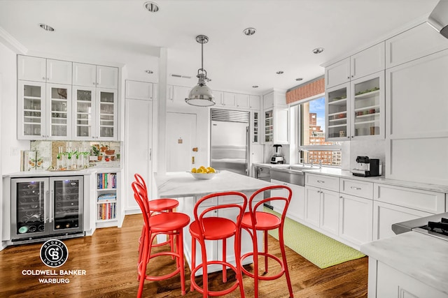 215 E 72nd St Unit 12E, New York City, NY 10021 - kitchen with built in refrigerator, a sink, beverage cooler, white cabinets, and wood finished floors