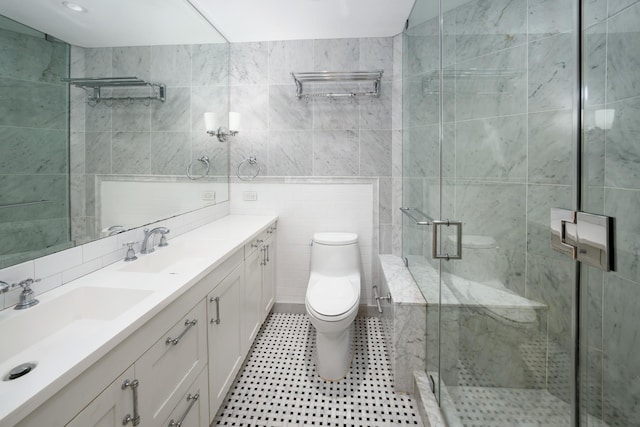 bathroom featuring a shower stall, toilet, tile walls, and double vanity