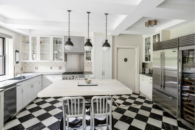 kitchen with appliances with stainless steel finishes, dark floors, a sink, white cabinetry, and coffered ceiling