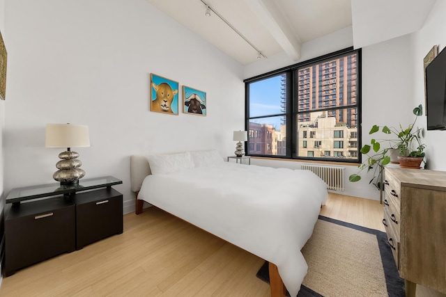 70 Washington St Unit 9A, New York City, NY 11201 - bedroom featuring radiator, light wood finished floors, and beamed ceiling