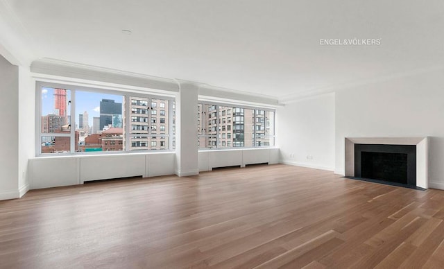 200 E 66th St Unit C1605, New York City, NY 10065 - unfurnished living room featuring wood finished floors, a fireplace with flush hearth, ornamental molding, a skyline view, and baseboards