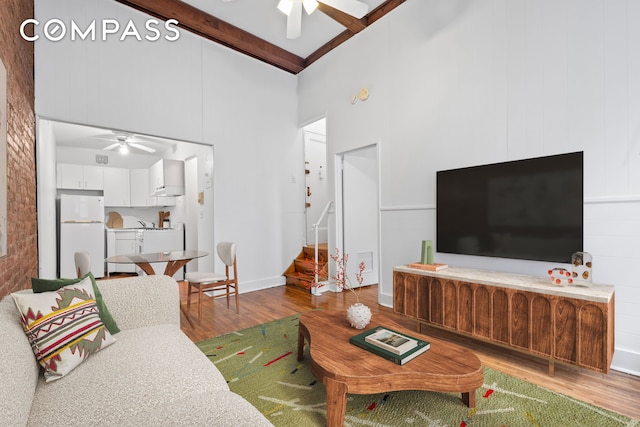 132 W 71st St Unit 3, New York City, NY 10023 - living room featuring ceiling fan, wood finished floors, a towering ceiling, stairs, and beamed ceiling