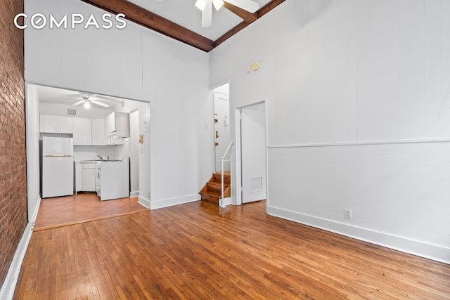132 W 71st St Unit 3, New York City, NY 10023 - unfurnished living room featuring a ceiling fan, beamed ceiling, a towering ceiling, hardwood / wood-style flooring, and stairs
