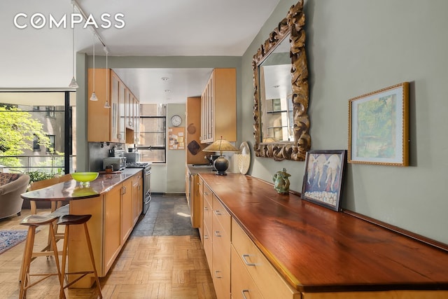 kitchen featuring wooden counters, stainless steel gas range oven, a breakfast bar, a sink, and a peninsula