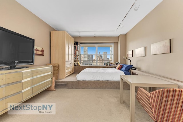 bedroom with rail lighting, light carpet, and a view of city