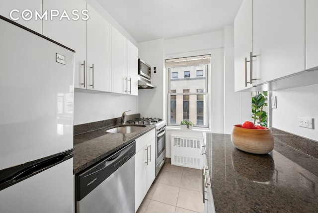 kitchen featuring stainless steel appliances, radiator, a sink, and white cabinetry