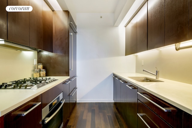 kitchen with stainless steel appliances, a sink, dark wood-style flooring, light countertops, and modern cabinets