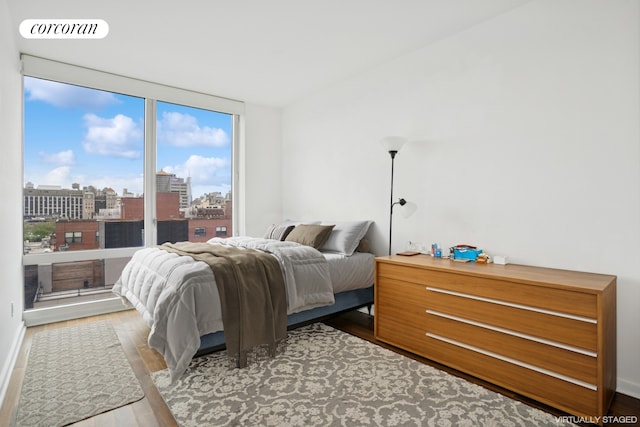 bedroom with wood finished floors and a view of city
