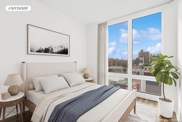 bedroom featuring wood finished floors, expansive windows, and a city view