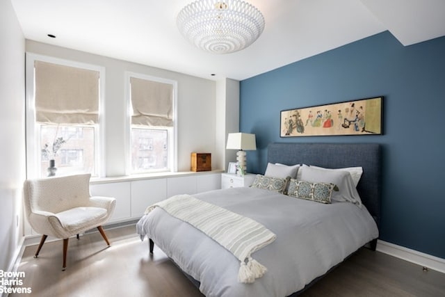 bedroom featuring wood finished floors, baseboards, and a chandelier