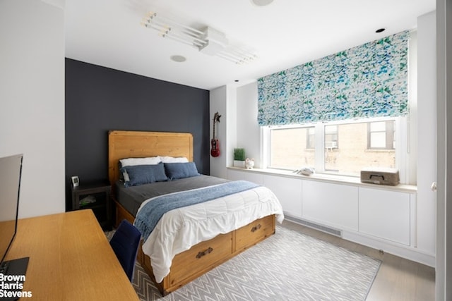 bedroom featuring wood finished floors and an accent wall