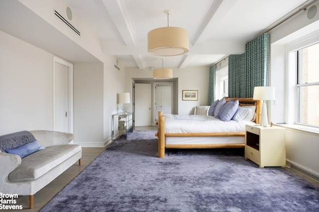 bedroom with beamed ceiling, baseboards, and wood finished floors
