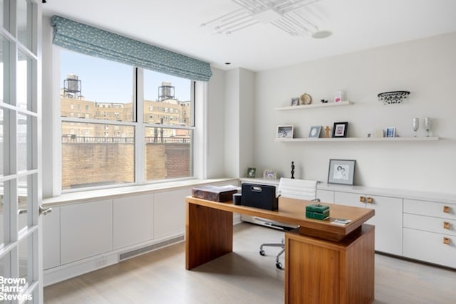 home office with light wood-style flooring and a city view