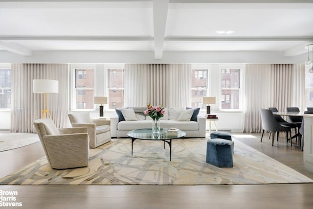 living area featuring beamed ceiling and wood finished floors