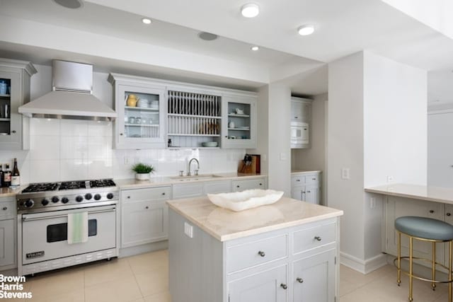 kitchen featuring white appliances, wall chimney exhaust hood, a sink, light tile patterned floors, and decorative backsplash