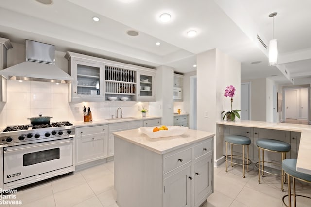 595 W End Ave Unit 9Fl, New York City, NY 10024 - kitchen with luxury range, wall chimney exhaust hood, light tile patterned flooring, tasteful backsplash, and a breakfast bar area