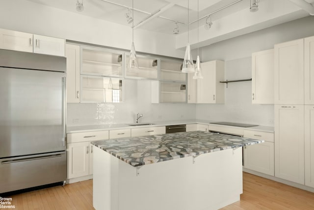 kitchen featuring stainless steel appliances, a sink, light wood finished floors, backsplash, and a breakfast bar area