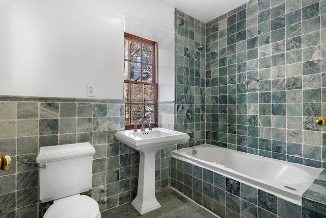 245 E 52nd St, New York City, NY 10022 - bathroom featuring tile walls, toilet, tiled shower / bath combo, tile patterned flooring, and wainscoting