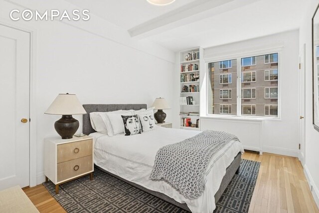 350 E 57th St Unit 14B, New York City, NY 10022 - bedroom featuring wood finished floors, beam ceiling, and baseboards