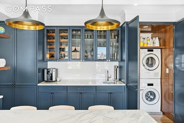 350 E 57th St Unit 14B, New York City, NY 10022 - indoor wet bar with stacked washer and clothes dryer, hanging light fixtures, backsplash, and crown molding
