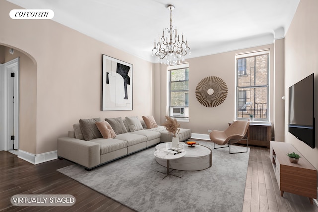 living room with arched walkways, baseboards, wood-type flooring, and a chandelier