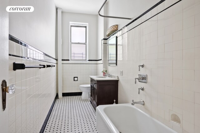 318 W 100th St Unit 1D, New York City, NY 10025 - full bath with tile walls, toilet, tile patterned floors, vanity, and a wainscoted wall