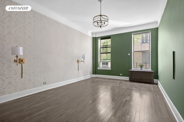 spare room featuring dark wood-type flooring, a chandelier, baseboards, and cooling unit