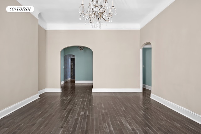 unfurnished living room featuring arched walkways, baseboards, and wood finished floors