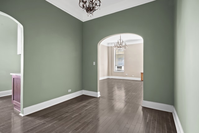 empty room featuring arched walkways, a chandelier, baseboards, dark wood-style floors, and ornamental molding