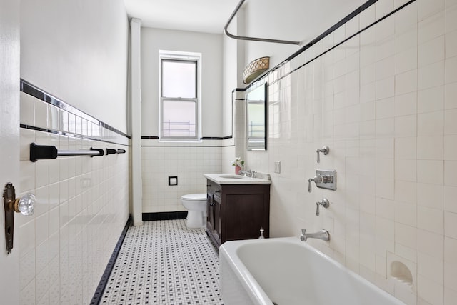 318 W 100th St Unit 1D, New York City, NY 10025 - bathroom with tile walls, toilet, tile patterned floors, vanity, and wainscoting